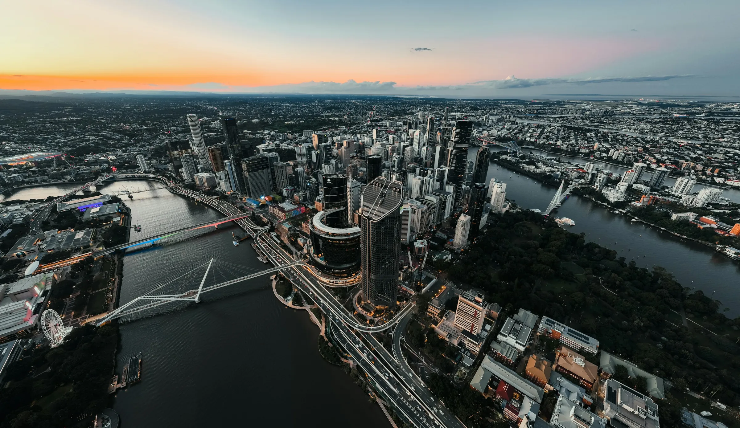 Aerial view of a city at dusk with river, bridges and roads